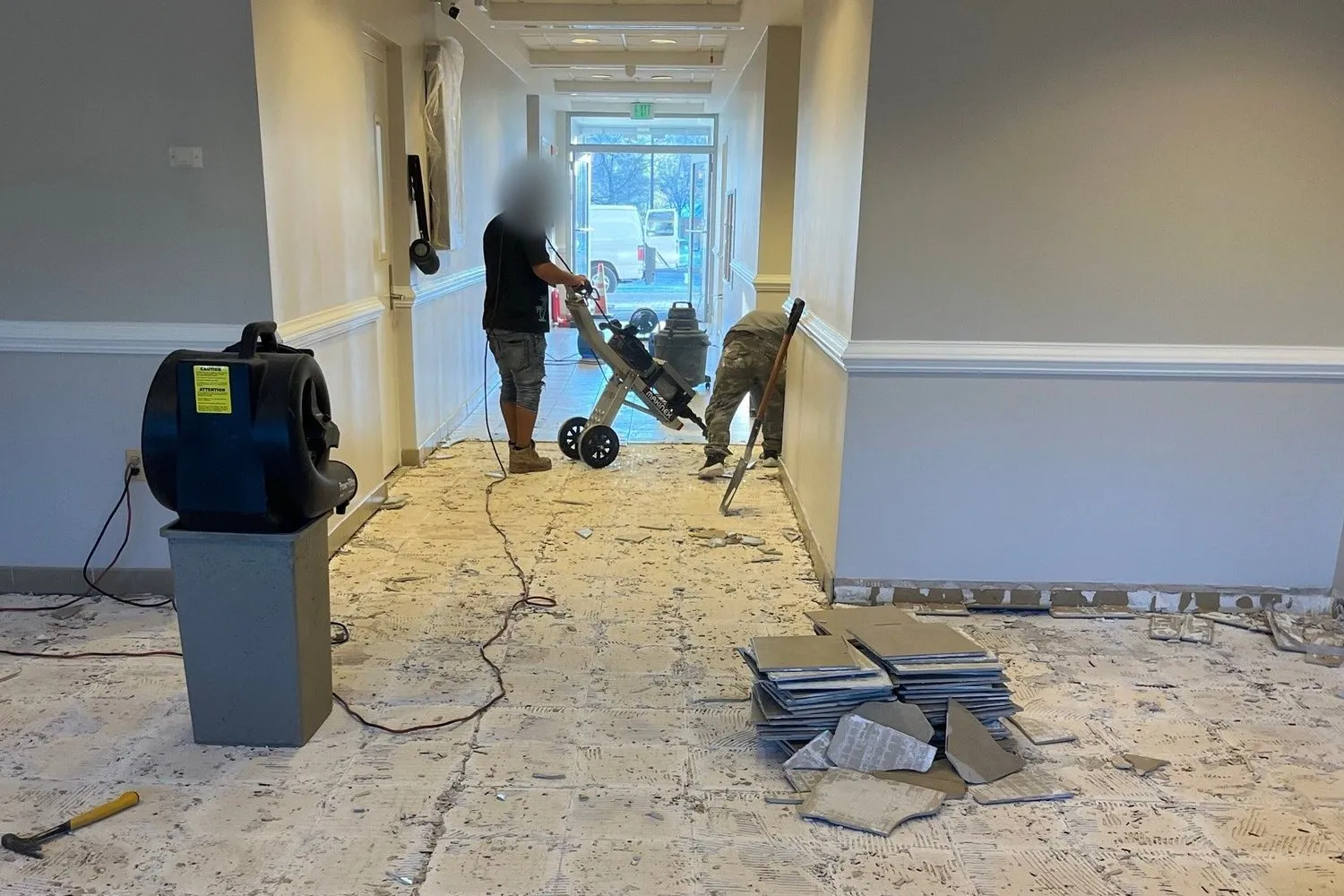 Office corridor with the old floor torn up, fans drying the slab